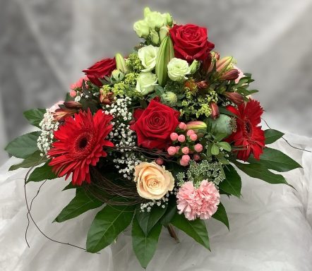 Bunter Blumenstrauß mit roten Rosen, Gerbera, und verschiedenen grünen Pflanzen.
