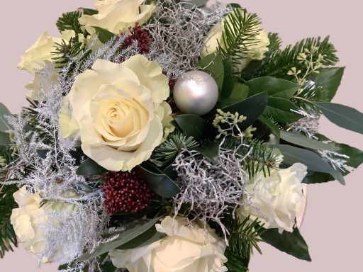 Ein Blumenstrauß mit weißen Rosen, grünen Blättern und silberner Dekoration.
