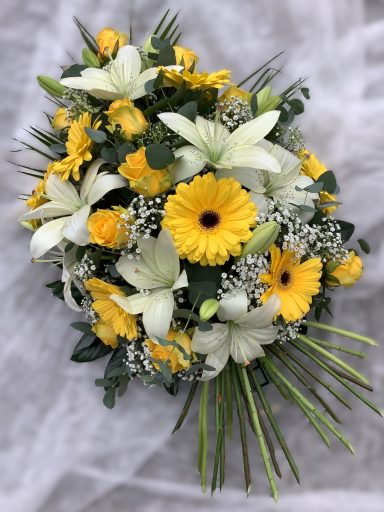 Bunte Blumenarrangement mit gelben Gerbera, Lilien und weißen Blüten.