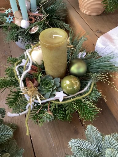 Ein Adventskranz mit einer grünen Kerze, Glaskugeln und Tannenzweigen.