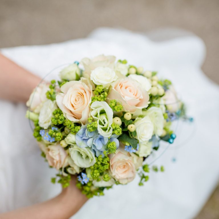 Ein rustikaler Tischaufsatz aus Holz mit einer Glasvase und weißen Blumen.